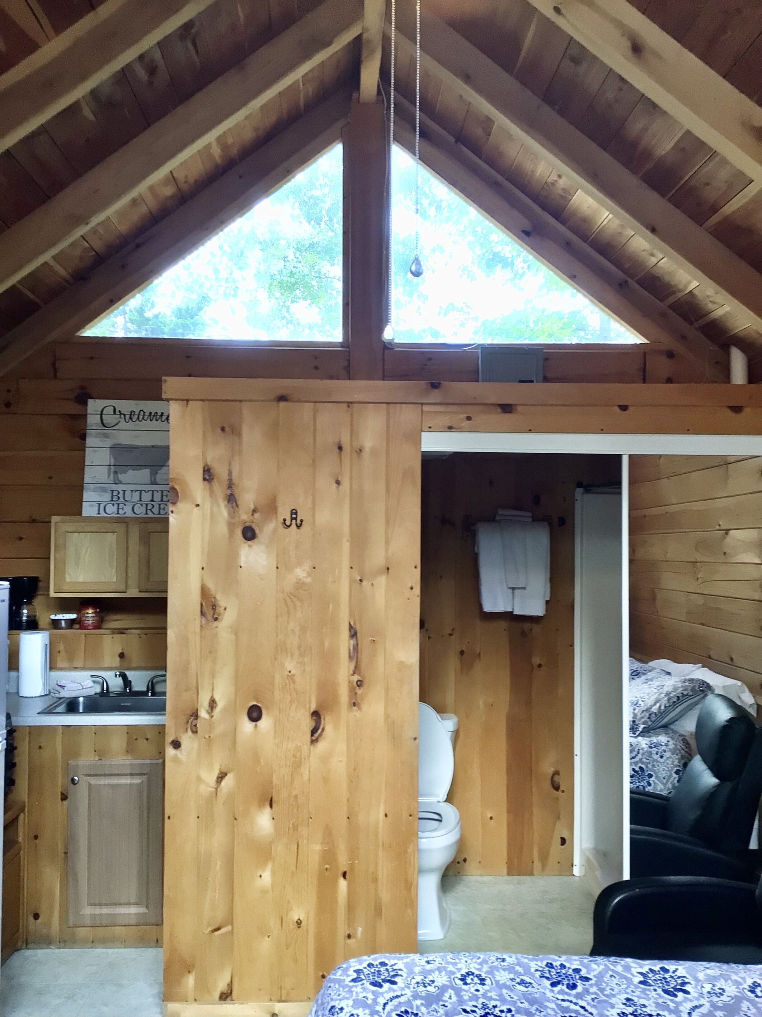 Eine rustikale Holzhütte mit Küchenbereich, Bad und Schlafbereich.