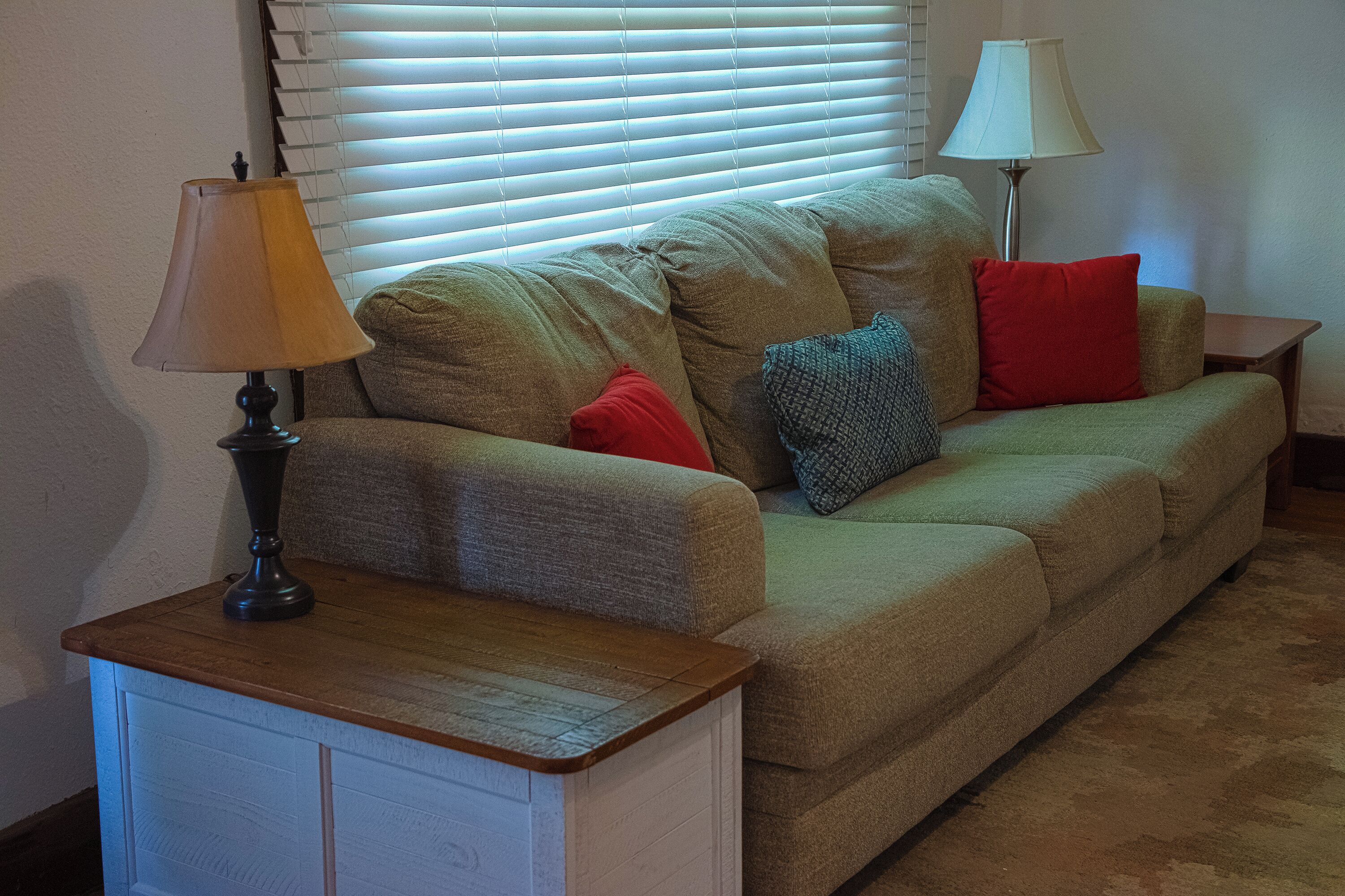 A living room with a sofa, two lamps, and a small table.