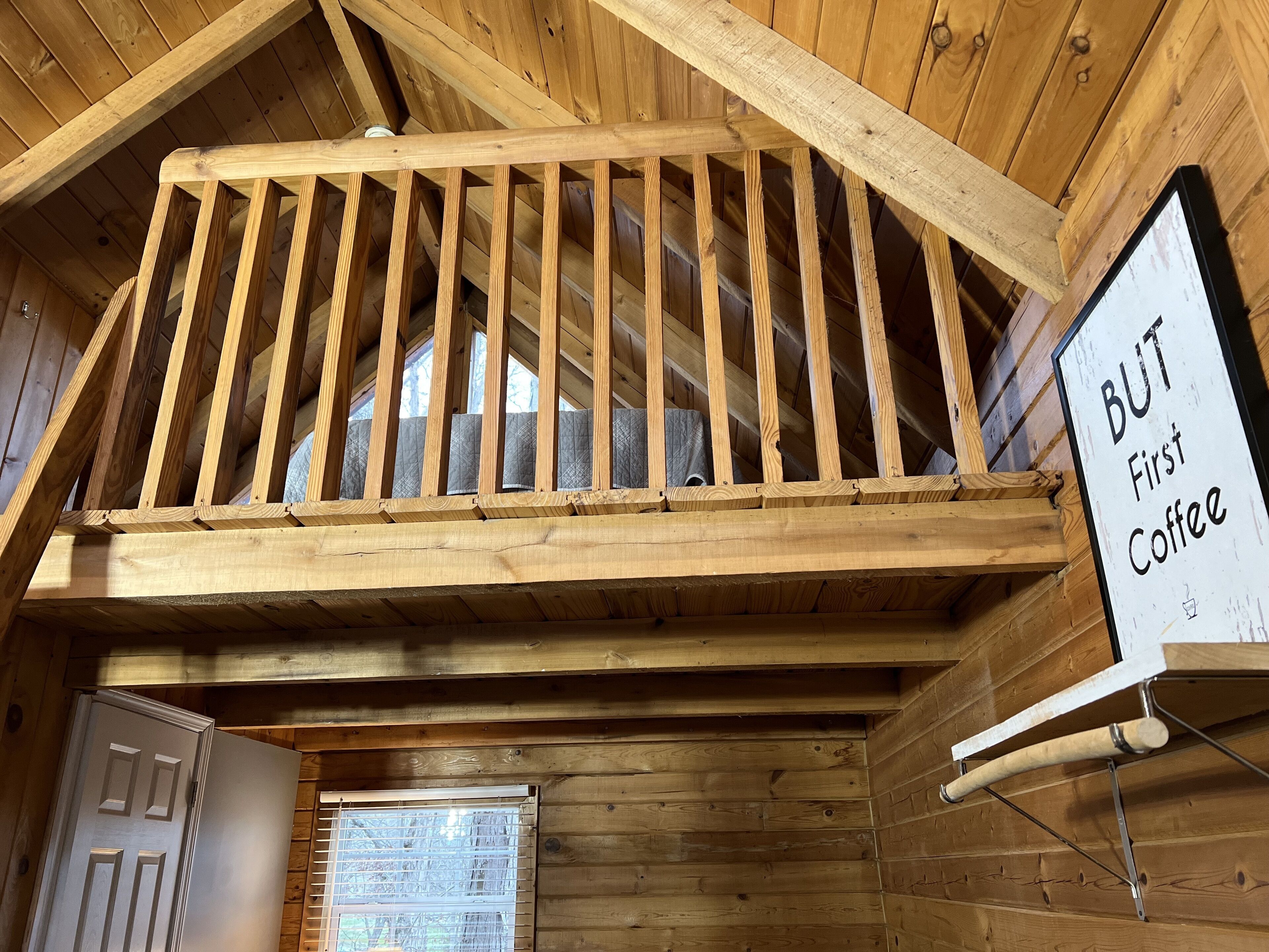 Un escalier en bois avec une pancarte sur laquelle on peut lire : « Mais d’abord, un café ».