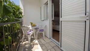 A balcony with a table and chairs, a sliding door, and a view of a garden. - Spacious apartment w. balcony, big garden & grill (Podglavica)