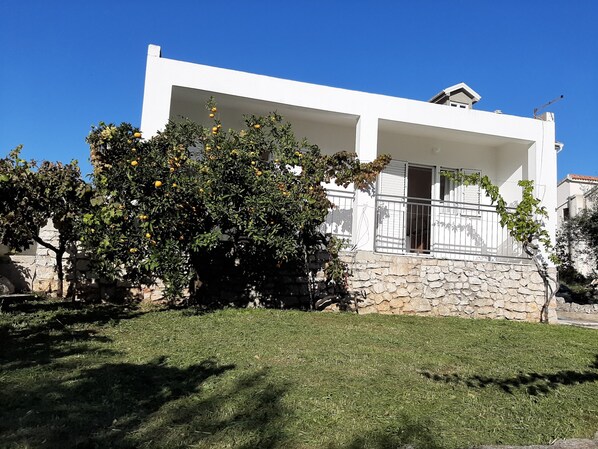 Une maison moderne à deux étages, avec des fondations en pierre et des murs extérieurs blancs.