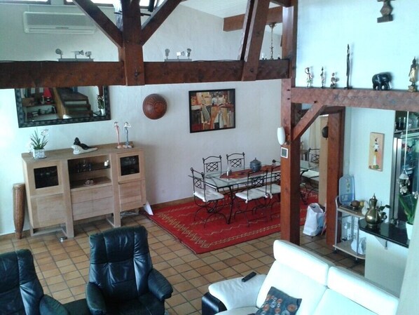 Ein Wohnzimmer mit Holzboden, einem Esstisch mit Stühlen, einer Couch und einem Schrank.
