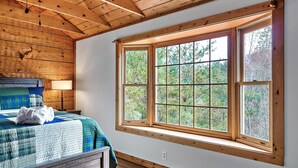A bedroom with a large window, wooden ceiling beams, and a bed with a blue and white quilt. - Amazing Wild Escape!-3Full Baths,Game,Hot Tub,Pets (Sevierville)