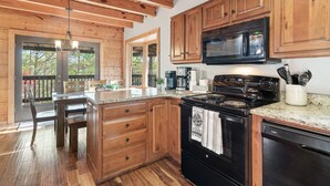 A kitchen with wooden cabinets, a black stove, and a microwave. - Amazing Wild Escape!-3Full Baths,Game,Hot Tub,Pets (Sevierville)