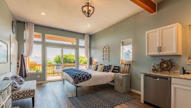Une chambre à coucher avec un lit, des tables de chevet, un bureau et une vue sur l’extérieur.