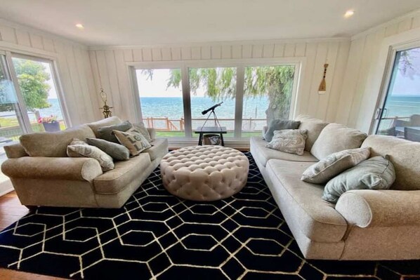 Relax in a serene ocean-view setting with a plush sofa and elegant ottoman on a geometric-patterned rug.