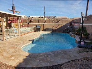 Enjoy a poolside retreat surrounded by a patio area and lush landscaping.