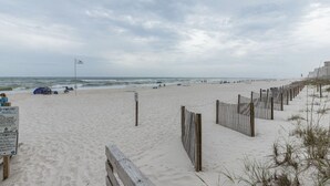 Ein Strand mit einer Holzlattenveranda, einem Zelt und einem Schild mit Strandregeln.
