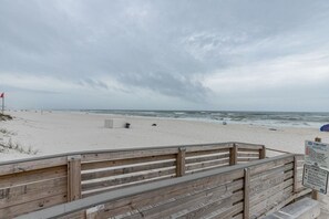 A wooden boardwalk leading to a sandy beach with a sign indicating beach warnings and a flag. - Flash Sale Completely updated 3/2 Sleeps 8 ML19 (Orange Beach)