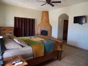 Cozy retreat with a large bed, dresser, TV, and fireplace.