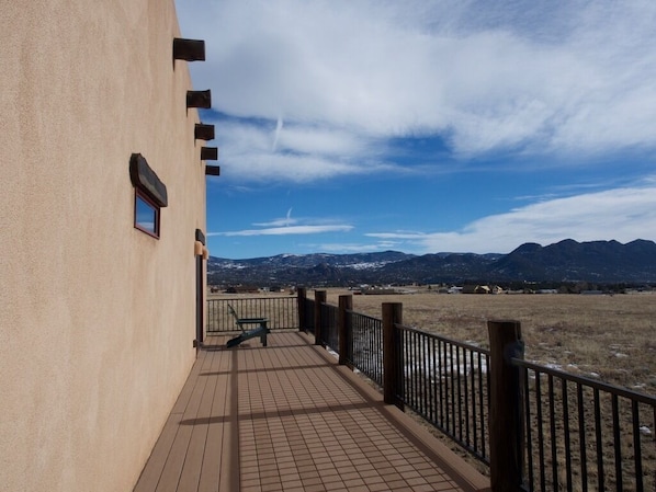 Enjoy breathtaking views of the surrounding mountains from this balcony, featuring a comfortable bench and a railing.