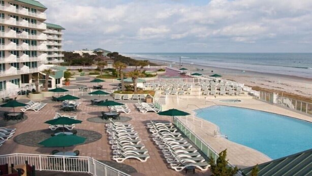 Un resort con piscina, tumbonas y vistas a la playa.