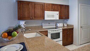 Una cocina con armarios de madera, microondas, estufa y pileta.