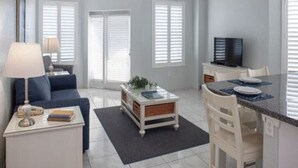 Un espacio habitable compacto con un sofá, una mesa de centro, una zona de comedor con sillas y un televisor.