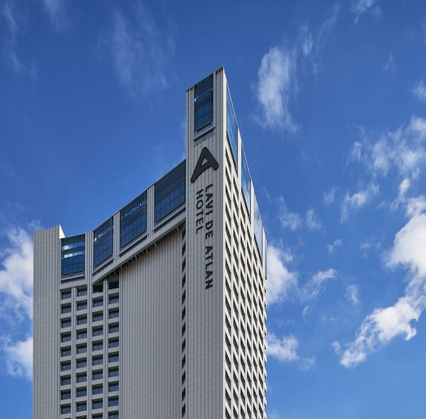 Un hotel de gran altura con un llamativo logotipo 'A' en el lateral, varios pisos y grandes ventanales.
