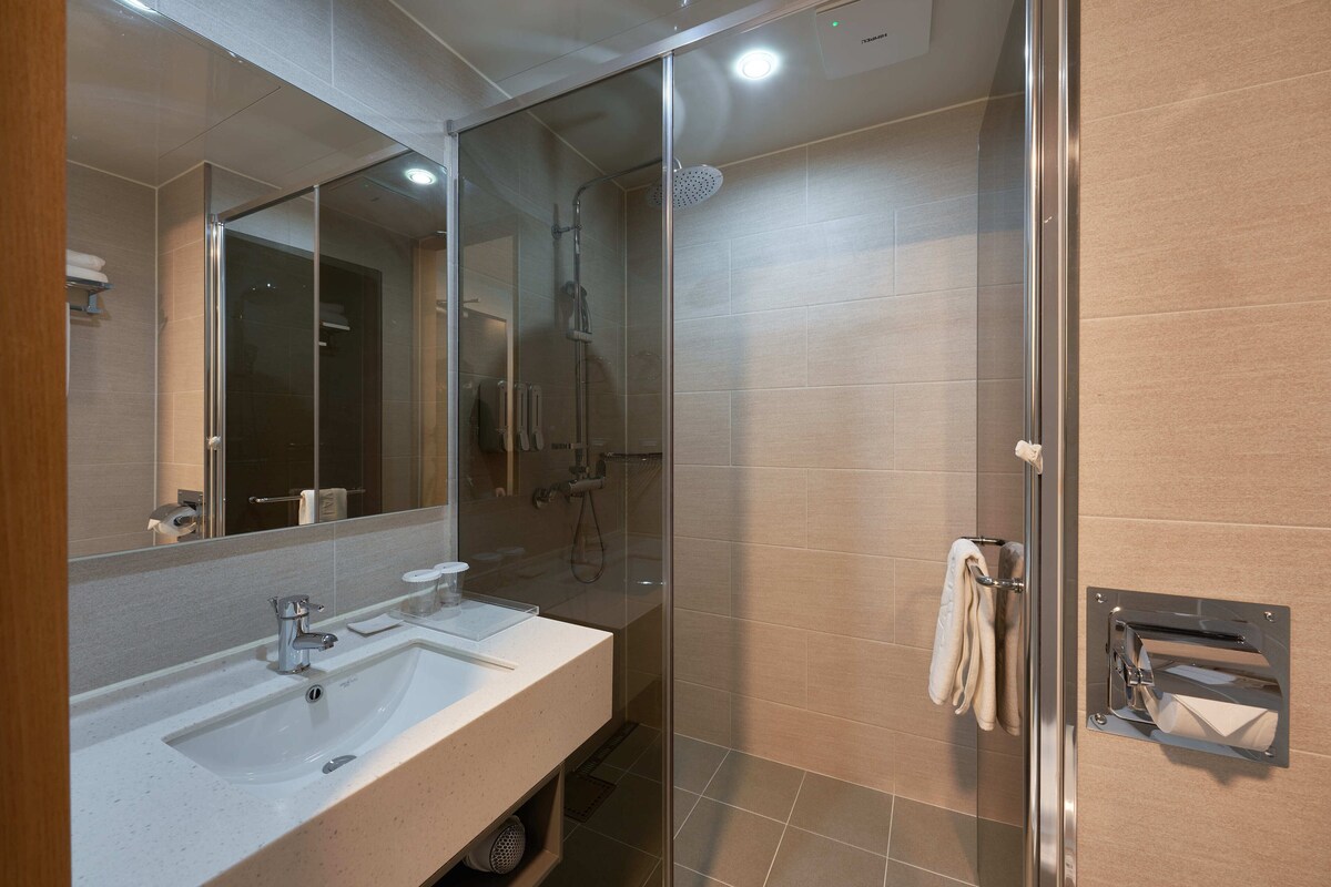 A modern bathroom with a glass-enclosed shower, a sink with a mirror, and a towel rack.
