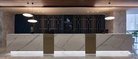 Una recepción con encimeras de mármol y diseño moderno, que muestra el logotipo y el nombre del hotel.