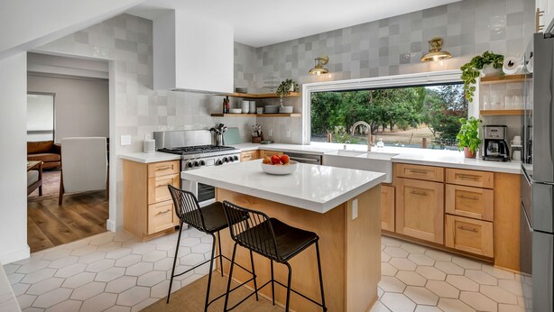 Uma cozinha moderna com uma ilha grande, armários de madeira e vista para o exterior.