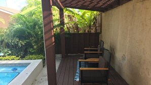 Et overdækket udendørsområde med pool, træterrasse og siddepladser.