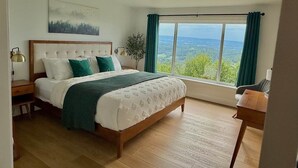 A bedroom with a large bed, a nightstand, a desk, and a view of the outdoors. - A-frame W/ Hot-tub, Mountain View & tennis court (Newport)
