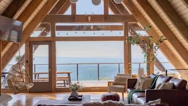 A spacious loft with a high ceiling and wooden beams, featuring a large window with a view of the landscape. - A-frame W/ Hot-tub, Mountain View & tennis court (Newport)
