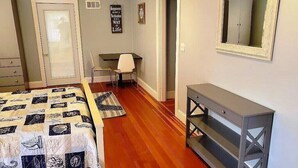 Un dormitorio con cama, escritorio, silla, cómoda y mesa consola.