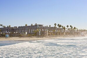 Een strandhotel met meerdere verdiepingen, balkons en palmbomen.