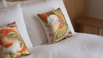 A bed with white linens and two decorative pillows with intricate patterns.