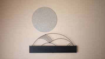 A wall-mounted art piece with a circular object and a black rectangular base.