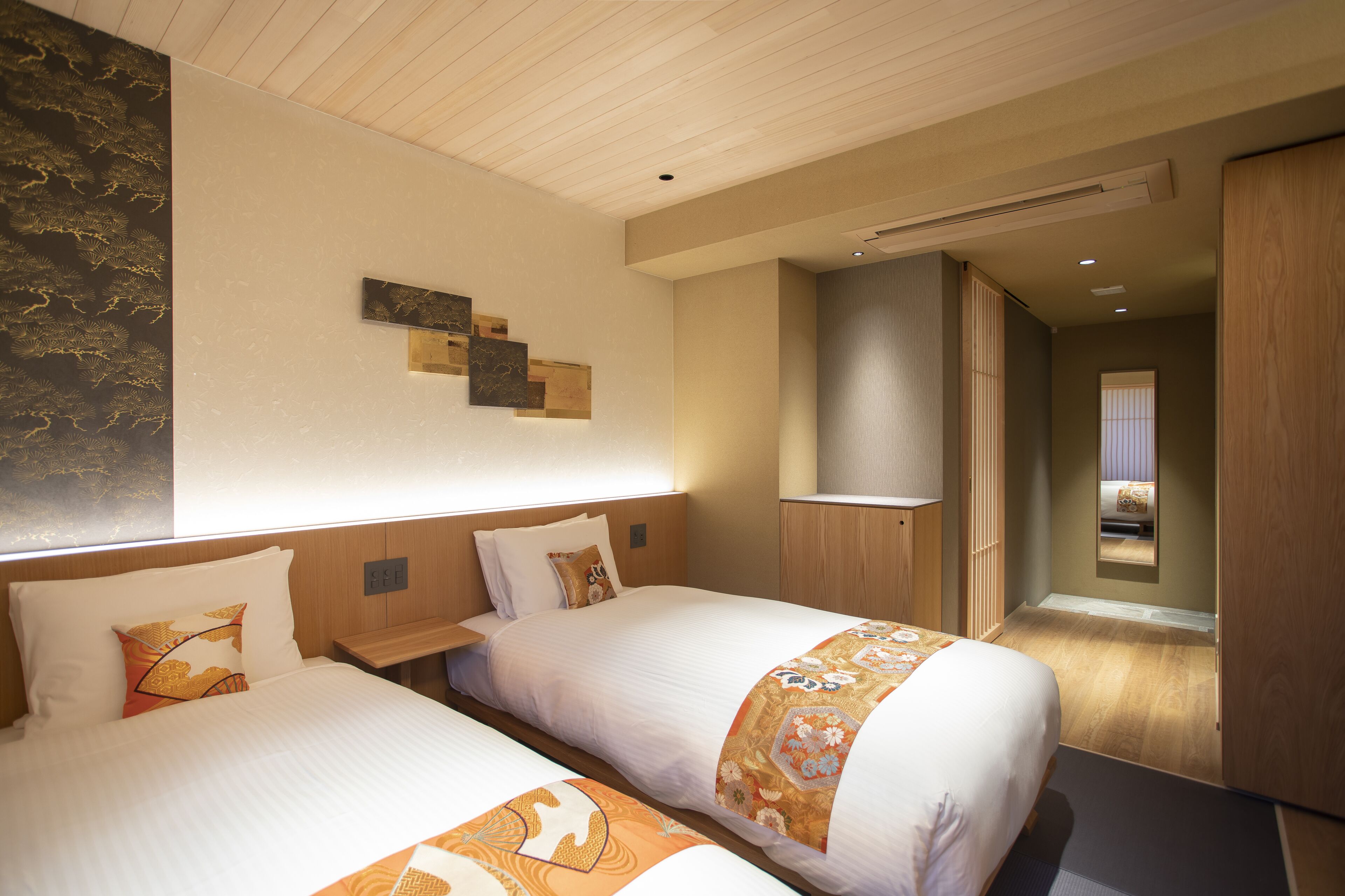 Une chambre d’hôtel avec deux lits, des têtes de lit en bois, un grand miroir et une armoire en bois.