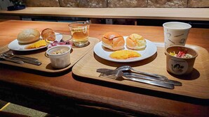 Uma mesa de madeira com pratos de comida, um copo de água e uma chávena com o logótipo de café.