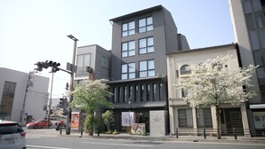 Um edifício moderno com entrada destacada, janelas amplas e uma placa indicando que é um hotel.