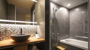 Casa de banho moderna com uma bacia grande, chuveiro manual e banheira separada.