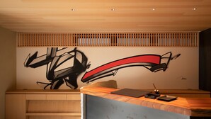 Uma receção com acabamento em madeira, uma obra de arte na parede e um design simples e sóbrio.