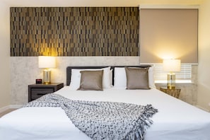 A neatly made bed with a patterned throw, two bedside lamps, and a textured wall behind. - Beautiful 6 Bedroom Home w/ Private Pool and Spa at Windsor Island (Davenport)