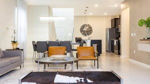 A modern living room with a sofa, a coffee table, and a dining area with chairs. - Beautiful 6 Bedroom Home w/ Private Pool and Spa at Windsor Island (Davenport)