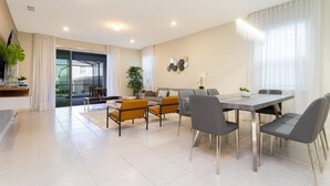 A modern dining area with a large table, grey chairs, and a potted plant. - Beautiful 6 Bedroom Home w/ Private Pool and Spa at Windsor Island (Davenport)