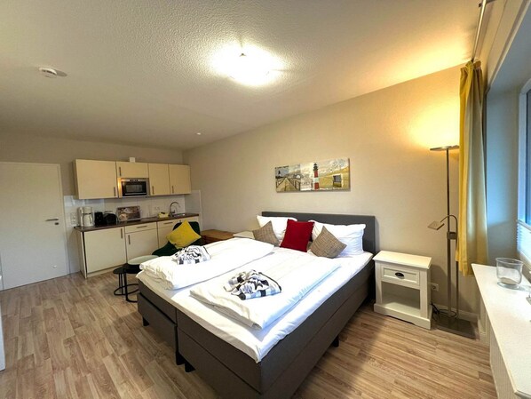 Une chambre d’hôtel moderne équipée d’un lit, d’une table de chevet et d’une petite kitchenette.