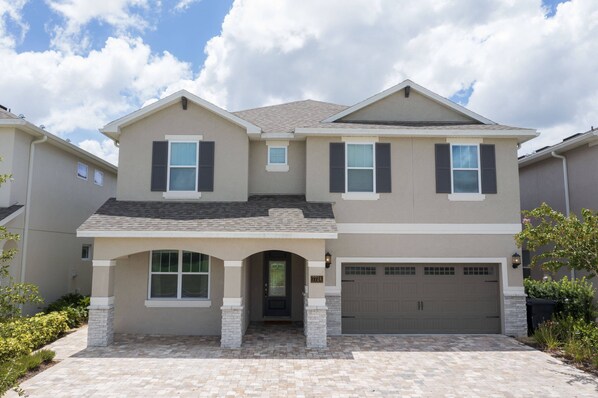 A two-story house with a garage, a covered entryway, and a brick driveway.