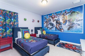 Quarto com duas camas, um mural de super-heróis na parede e um tapete do Homem-Aranha.
