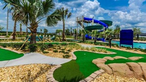 A water park with a blue water slide, palm trees, and a pool. - Modern Single Home - Pool and Game Room (Kissimmee)