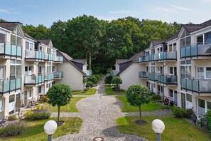 A row of modern apartment buildings with balconies, a central pathway, and well-maintained greenery. - Only 100 m to the beach, apartment with balcony and terrace - App. Eldena FeWo 04 - (Middelhagen)