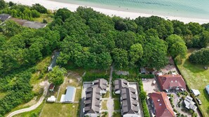 An aerial view of a residential area with a beach, dense greenery, and multiple houses. - Only 100 m to the beach, apartment with balcony and terrace - App. Eldena FeWo 04 - (Middelhagen)