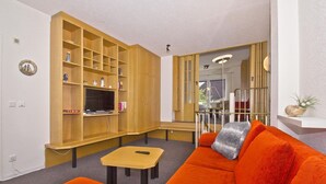A living room with a wooden entertainment unit, a sofa, and a small table. - Only 100 m to the beach, apartment with balcony and terrace - App. Eldena FeWo 04 - (Middelhagen)