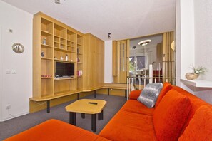 A living room with a wooden entertainment unit, a sofa, and a small table. - Only 100 m to the beach, apartment with balcony and terrace - App. Eldena FeWo 04 - (Middelhagen)