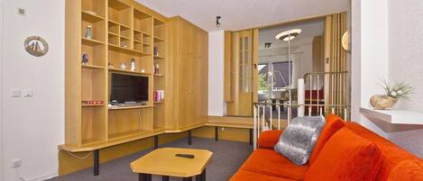 A living room with a wooden entertainment unit, a sofa, and a small table.
