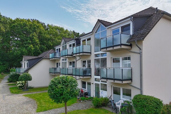 A multi-story residential building with balconies, a paved driveway, and surrounding greenery. - Only 100 m to the beach, apartment with balcony and terrace - App. Eldena FeWo 04 - (Middelhagen)