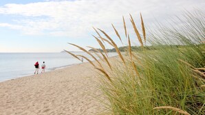A beach with sand, grass, and a person walking. - Vacation home Milan - waterfront vacation home with fireplace, sea view and garden - (Gager)