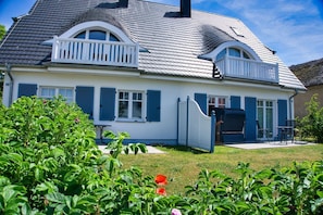 A two-story house with a dark roof, white walls, and blue shutters.