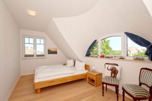 A bedroom with a wooden bed, a nightstand, two chairs, a window with curtains, and a picture on the wall. - Vacation home Milan - waterfront vacation home with fireplace, sea view and garden - (Gager)